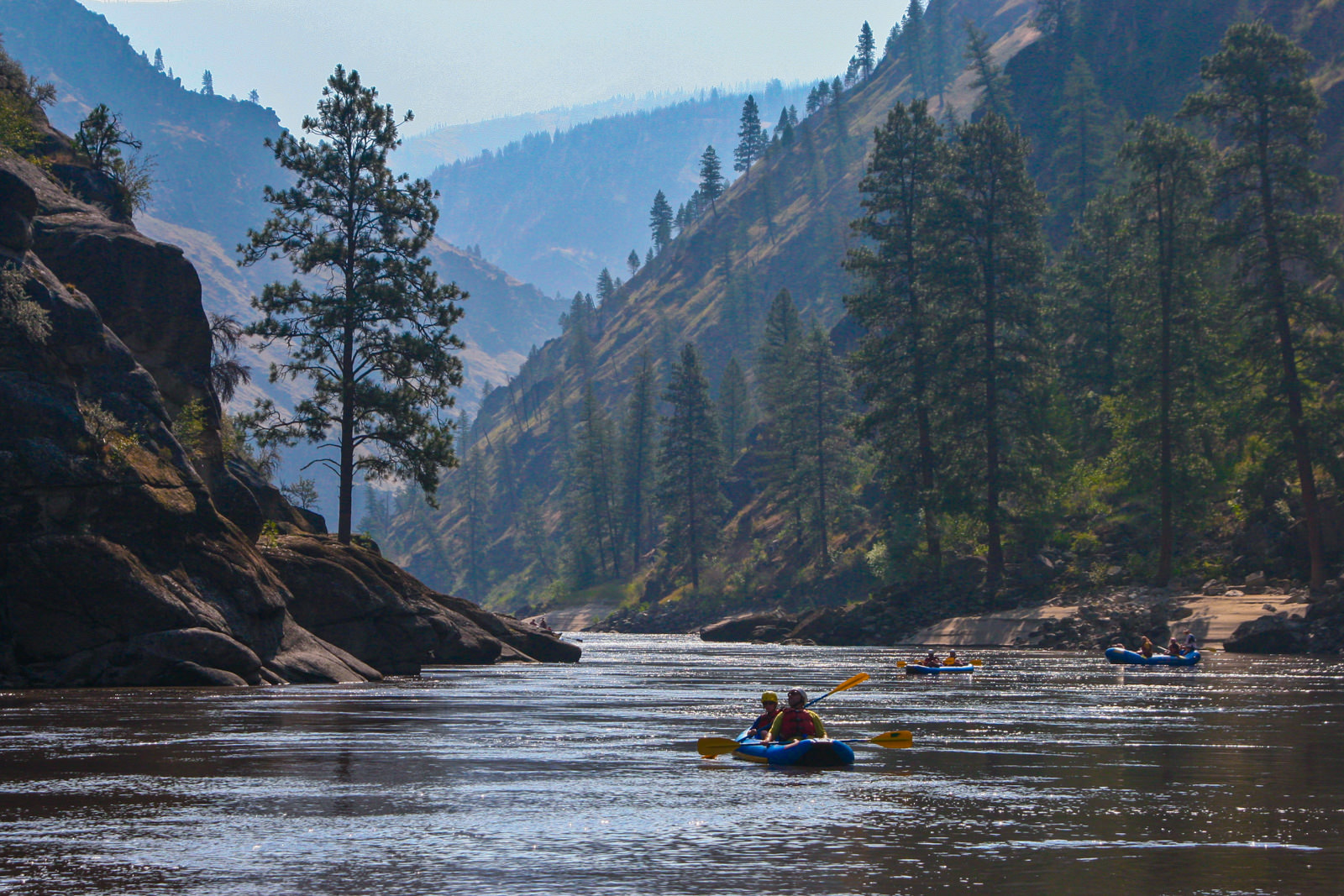 two people paddle along the main Salmon River in a raft